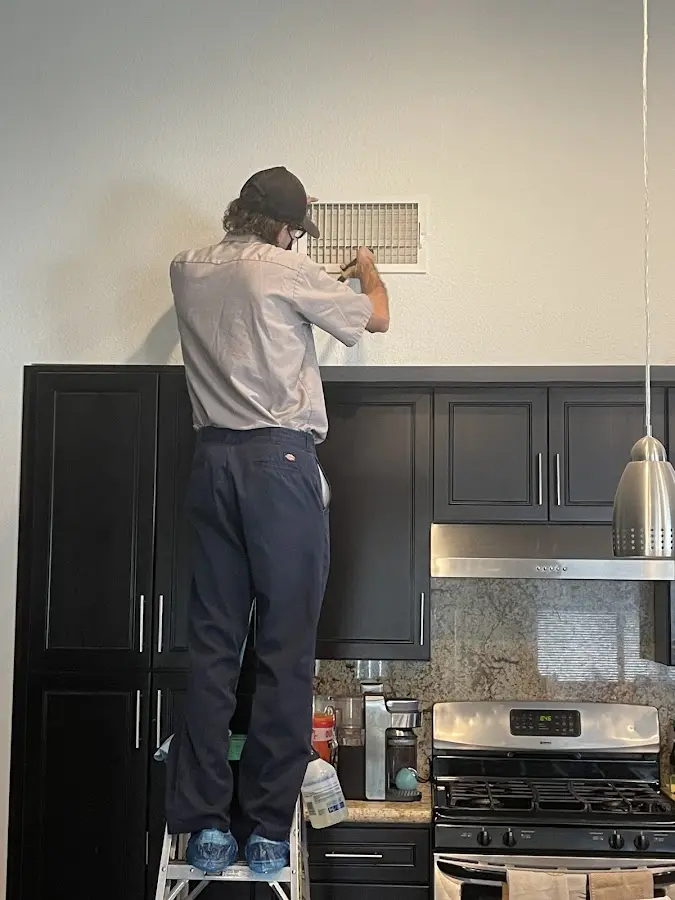 Technician inspecting an air vent during HVAC service in Erwin